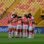 Equipe feminina de futebol reunida em círculo no campo antes de uma partida