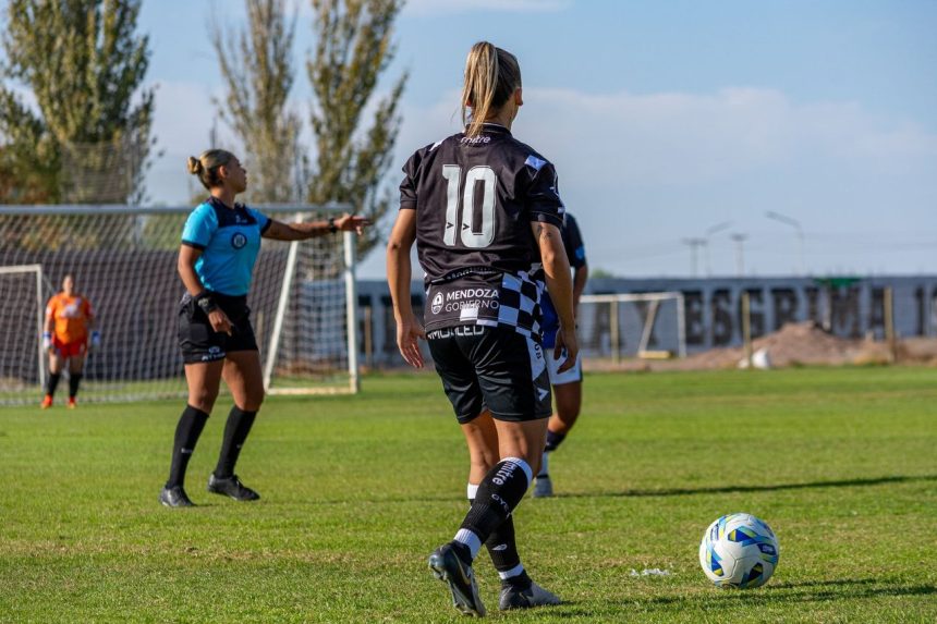 Jogadoras disputam uma partida de futebol feminino ao ar livre, sob luz do dia.