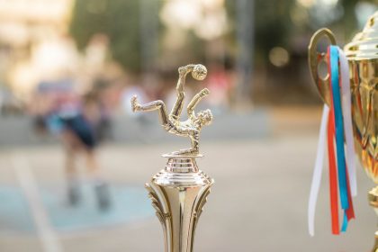 Troféu dourado de futebol com fitas, exposto como símbolo de vitória e premiação esportiva.