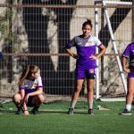 Grupo de jogadoras de futebol aquece em campo antes de uma partida.