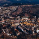 Vista aérea de Ouro Preto, com arquitetura histórica, áreas verdes e relevo montanhoso ao redor da cidade.