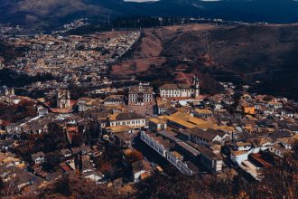 Vista aérea de Ouro Preto, com arquitetura histórica, áreas verdes e relevo montanhoso ao redor da cidade.